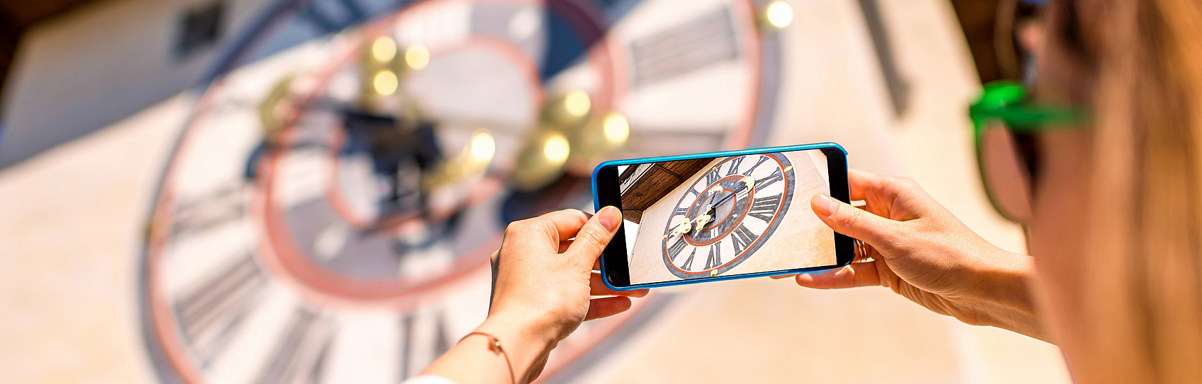 Frau fotografiert Uhrturm mit Smartphone