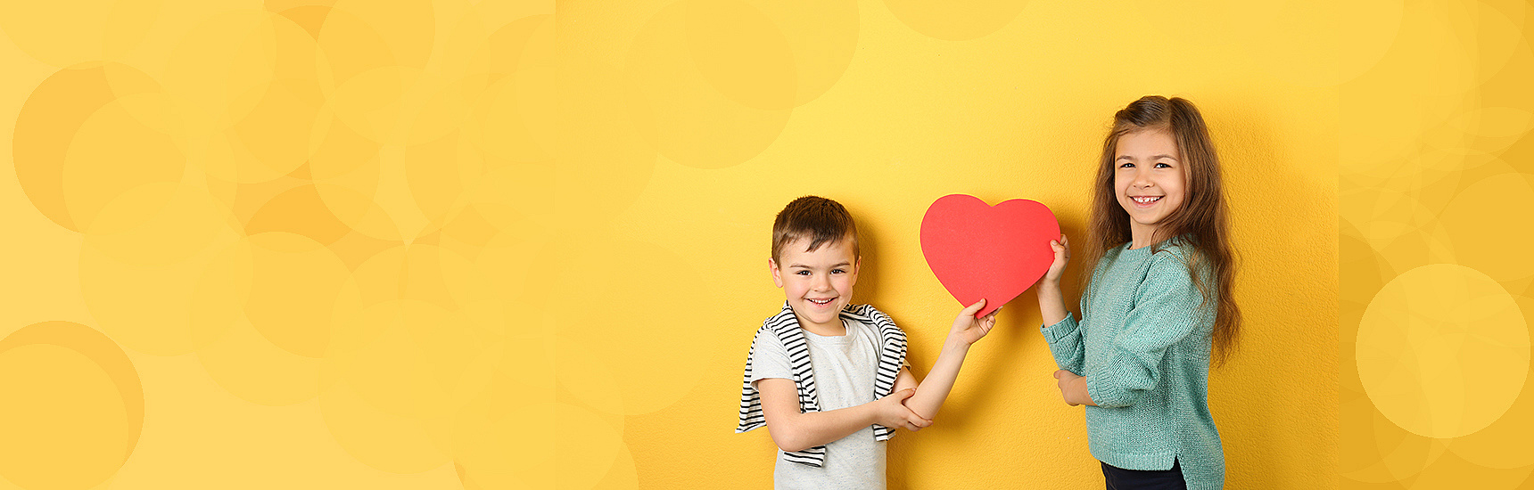 Zwei Kinder halten ein Herz aus Papier