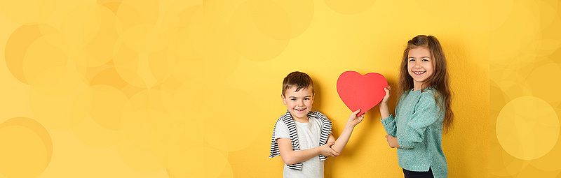 Zwei Kinder halten ein Herz aus Papier