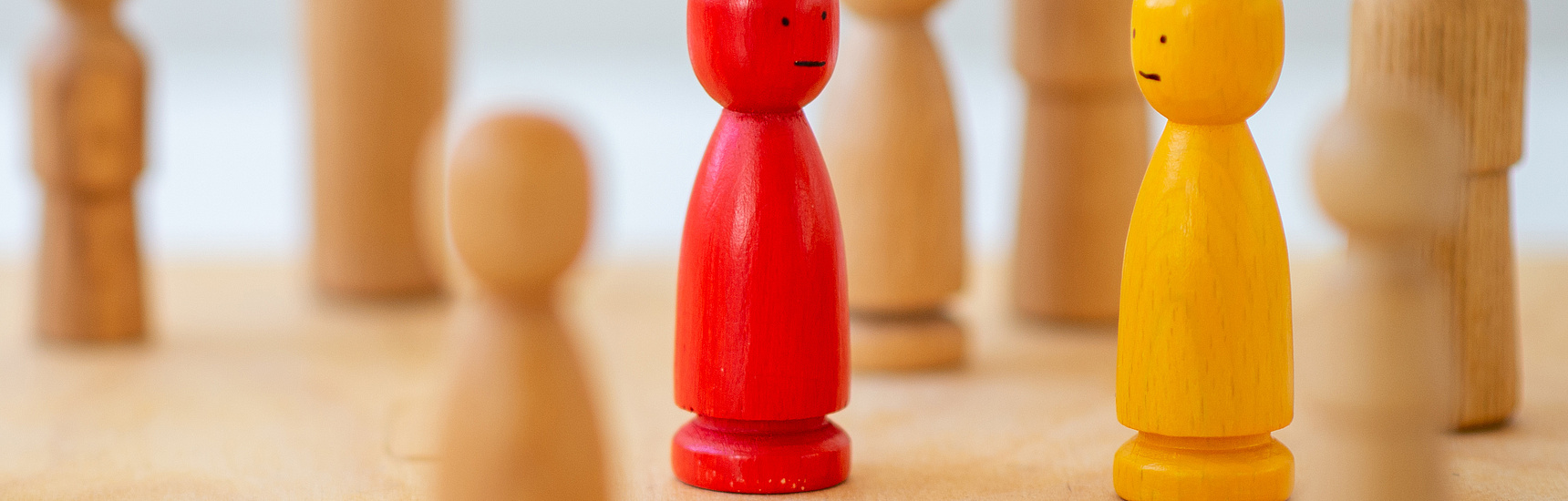 Holzfiguren auf Spielfeld als Symbol für systemische Therapie, Familientherapie