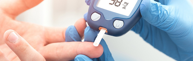 Arzt überprüft Blutzuckerspiegel mit Blutzuckermessgerät