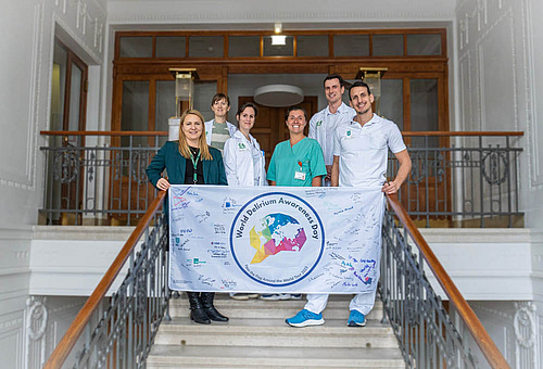 Mitarbeiter*innen des LKH-Univ. Klinikum Graz bzw. der Med Uni Graz mit der World Delirium Awareness Day Flagge 