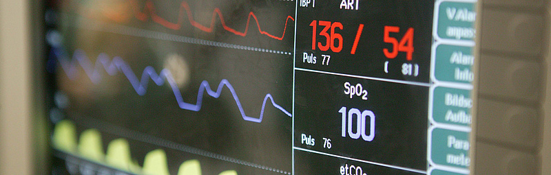 Auf einem Monitor werden Vitalzeichen wie Puls, Suaerstoffsättigung und Blutdruck angezeigt.