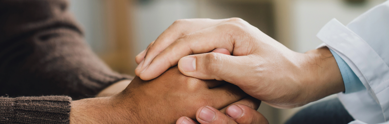Ein Psychiater hält die Hände eines Patienten fest